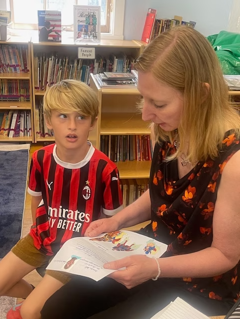 A student at Norma Coombs School reading a letter from his Senegal pen pal with his teacher
